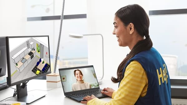 An IKEA co-worker in a yellow shirt talking to two people using a planning computer in a store’s kitchen department.