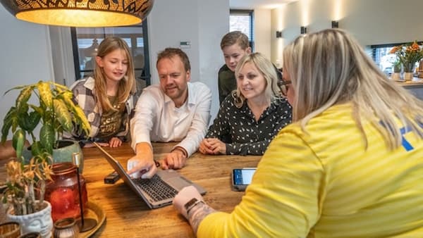 An IKEA co-worker in a yellow shirt talks to a mother, father and two children about planning a kitchen. 
