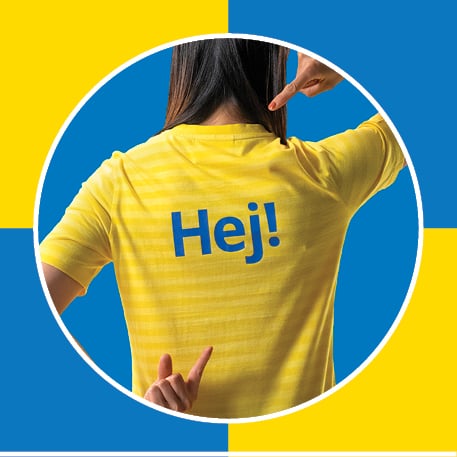 an ikea co-worker pointing to the back of their shirt that reads "Hej", on a blue and yellow checkered background