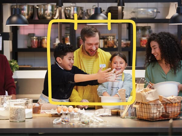 An IKEA co-worker wearing a yellow uniform having a cooking workshop with children in an IKEA store.