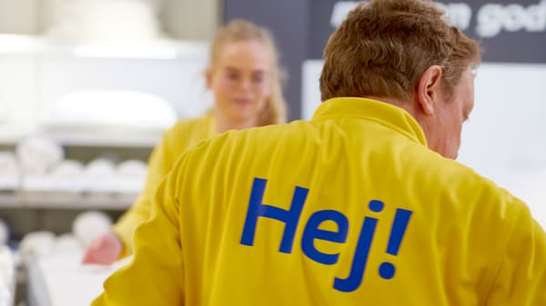 An IKEA co-worker wearing a yellow uniform with the word “Hej!” on the back of the shirt.