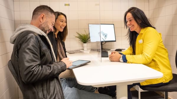 An IKEA coworker helping two customers at a desk on a computer