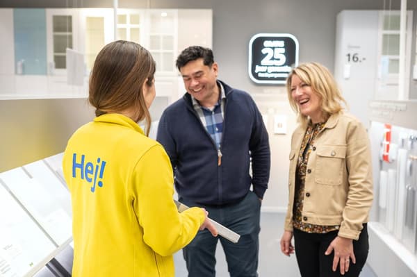An IKEA coworker in the kitchen planning area in store showing samples to two customers