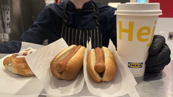 An IKEA coworker serving three hot dogs and a drink