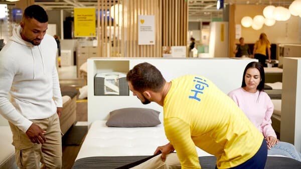 An IKEA coworker shows a couple a new mattress in store