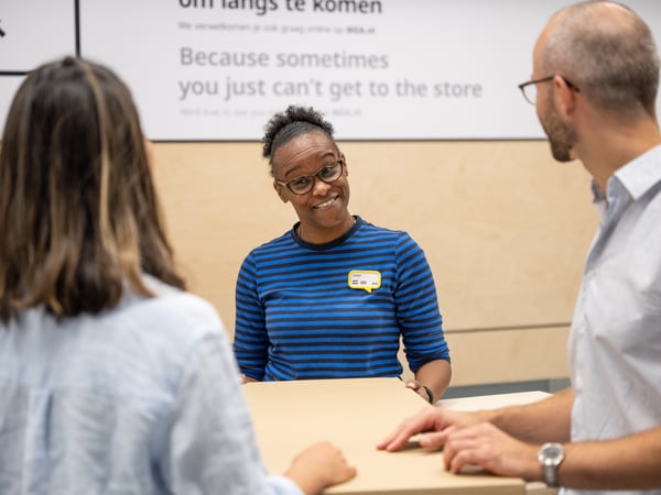 An IKEA customer service representative advises customers at the counter.