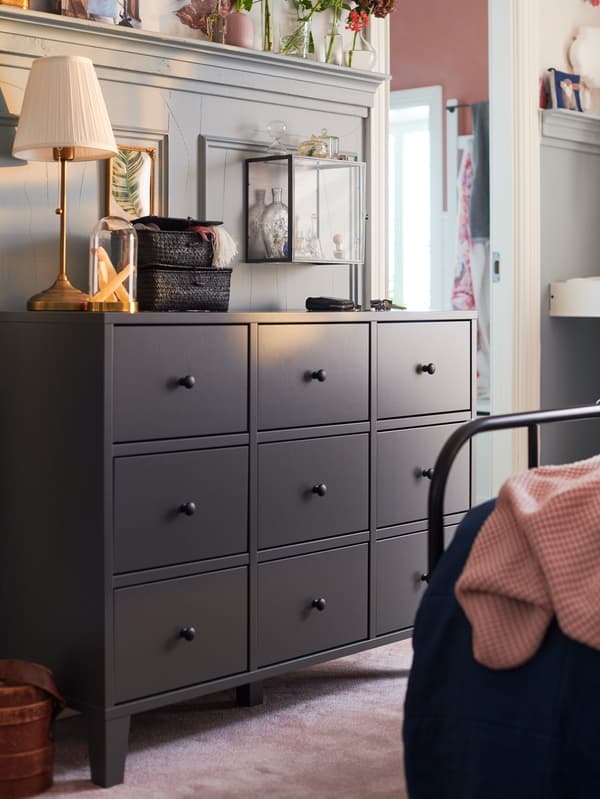 An IKEA dark grey dresser with nine drawer units in a bedroom setting.