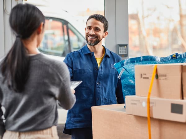 An IKEA delivery man hands a customer her IKEA order from several parcels.