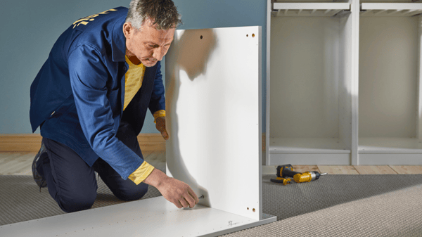 An IKEA employee assembles a PAX wardrobe