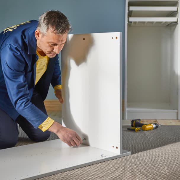 An IKEA employee assembles a PAX wardrobe