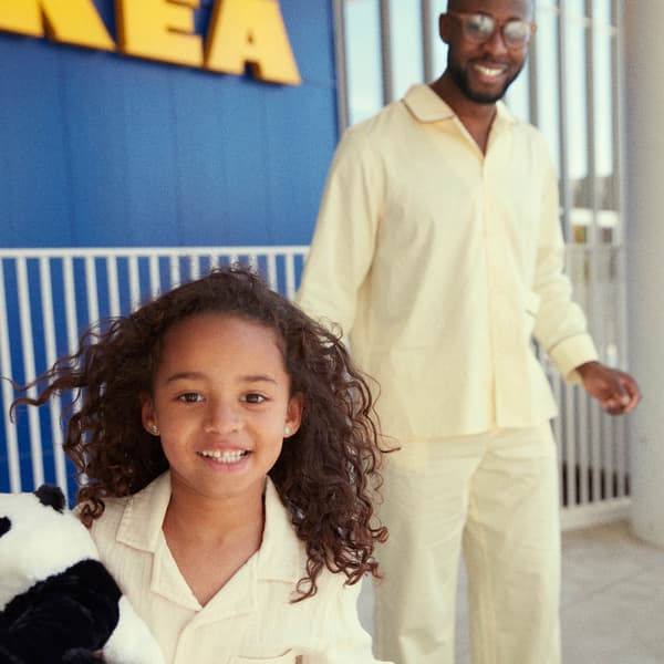 An IKEA employee behind a desk with her back turned to the camera, assisting a man and a woman in the service department.