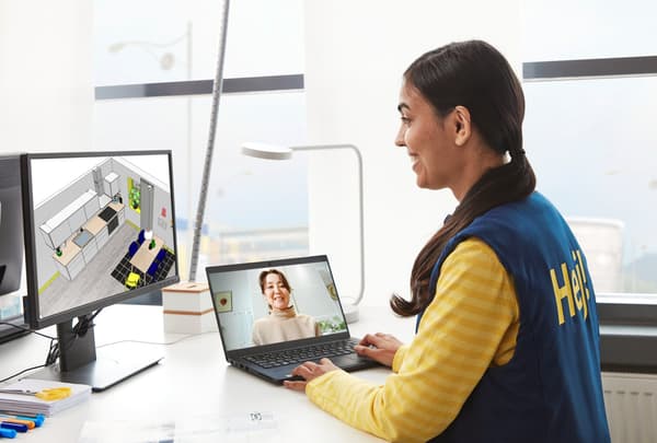 An IKEA employee holding an online kitchen plan with a customer on her laptop