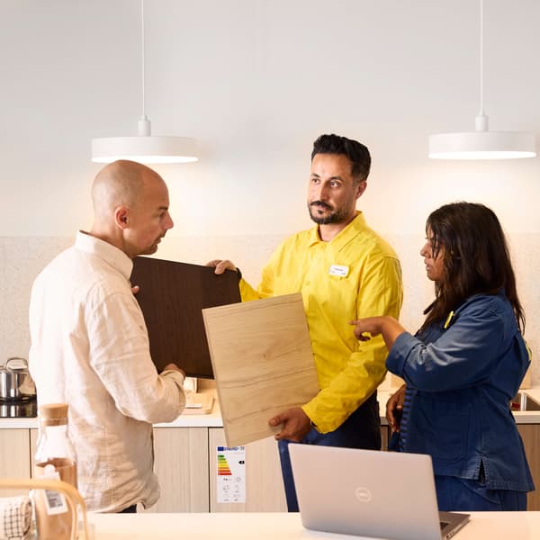 An IKEA employee shows various fronts to a customer in the kitchen department.