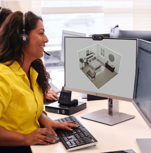 An IKEA employee sits on front of a screen with a headset on