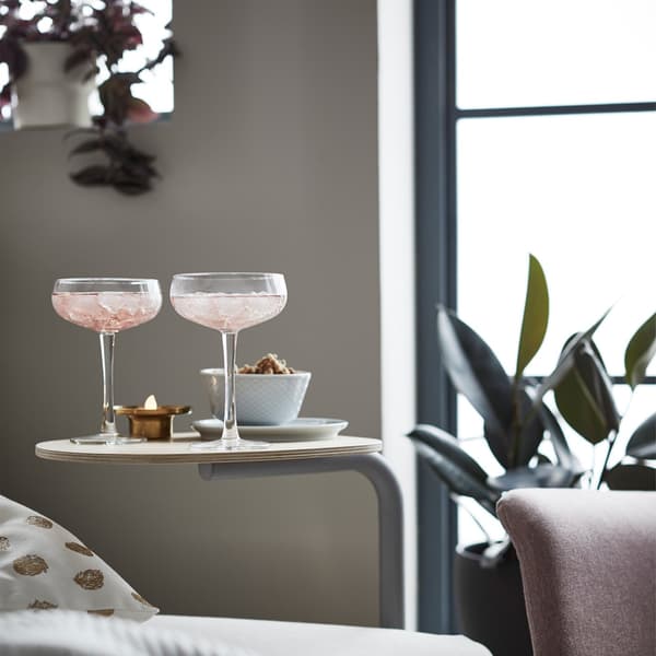 An IKEA FLOTTEBO side table attached to the sofa with glasses on it.