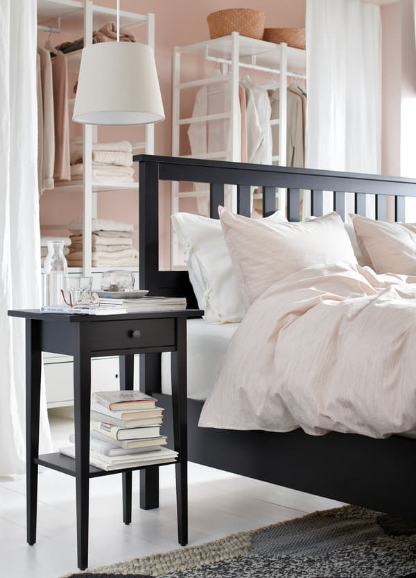 An IKEA HEMNES black brown bed frame with a slatted headboard, bedside table and pink bedding.