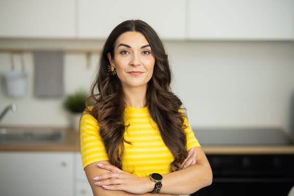 An IKEA interior designer wearing a yellow work T-shirt smiles at the camera; an IKEA kitchen is visible in the background.