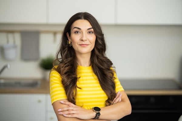 An IKEA interior designer wearing a yellow work T-shirt smiles at the camera; an IKEA kitchen is visible in the background.