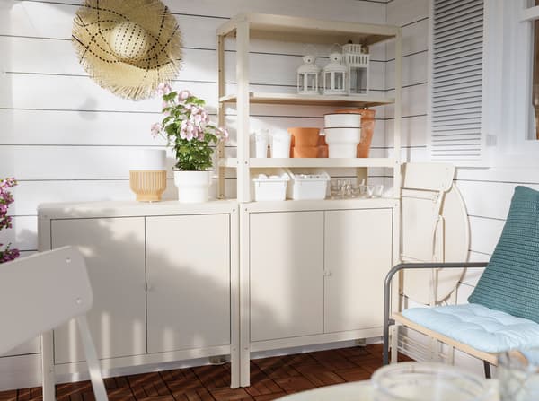 An IKEA KOLBJÖRN indoor and outdoor shelving unit displaying pots, lanterns and flowers.