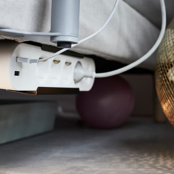 An IKEA KOPPLA power strip placed underneath a sofa.