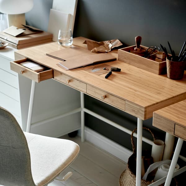 An IKEA LILLÅSEN desk in bamboo with white legs in a home office with dark walls