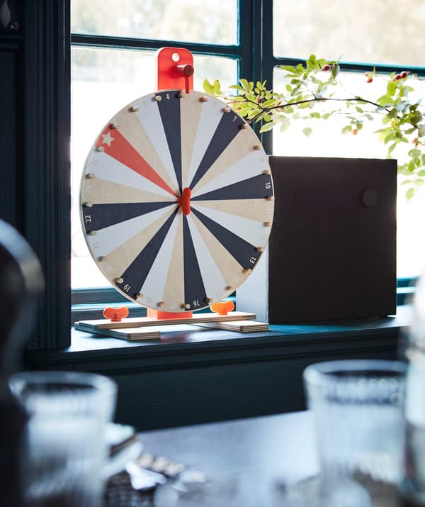 An IKEA LUSTIGT wheel of fortune game placed on a window sill.