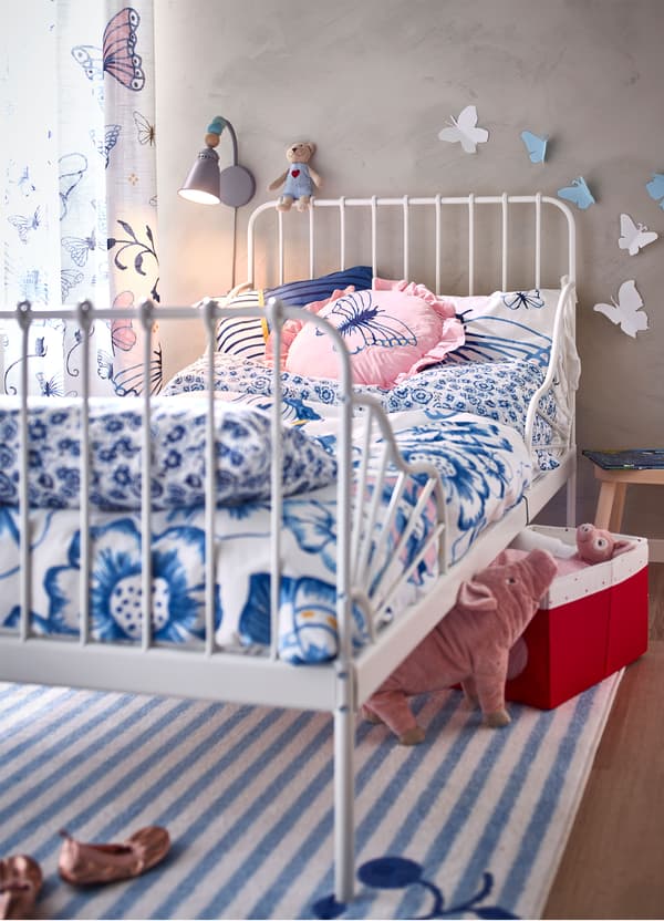 An IKEA MINNEN white extendable bed frame and SÅNGLÄRKA blue and white butterfly patterned bedlinen.