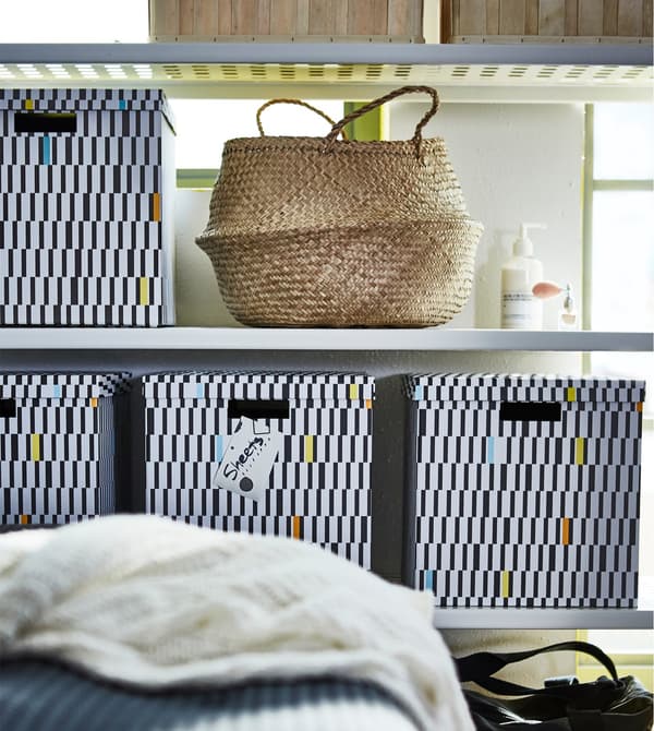An IKEA MULIG shelving unit stacked with IKEA TJENA boxes and a basket.