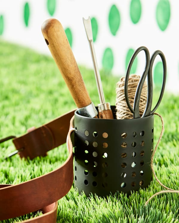 An IKEA ORDNING utensil holderturned into a gardening tool belt sits in the grass.