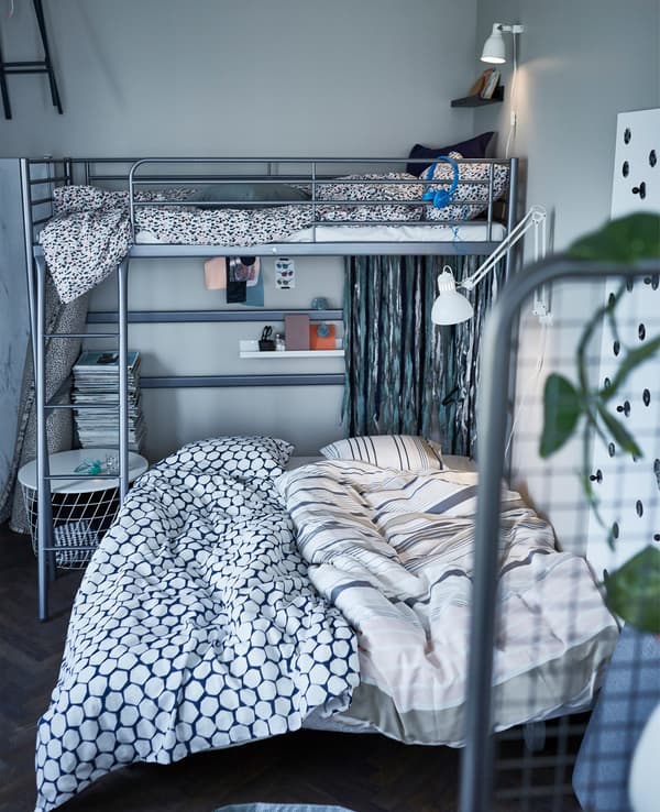 An IKEA PS LÖVÅS sofa bed on castors set up as a double bed underneath a loft bed.