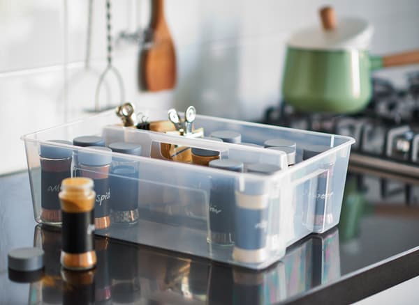An IKEA SAMLA box filled with jars of herbs and spices on a kitchen worktop.