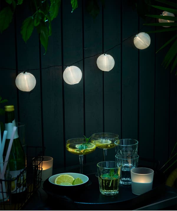An IKEA SOLARVET lighting chain hanging above a selection of drinking glasses.