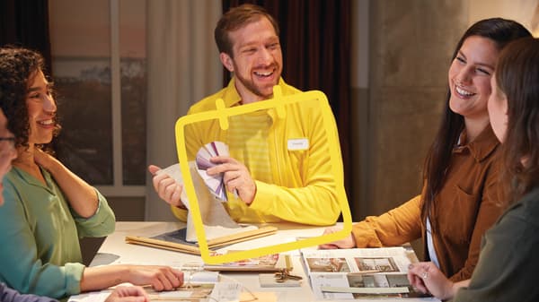 An IKEA staff member in a yellow shirt consulting with a customer while showing color samples.