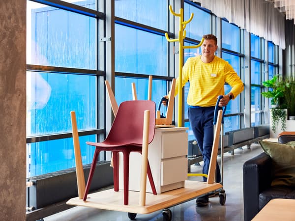 An IKEA staff member transporting furniture on a cart