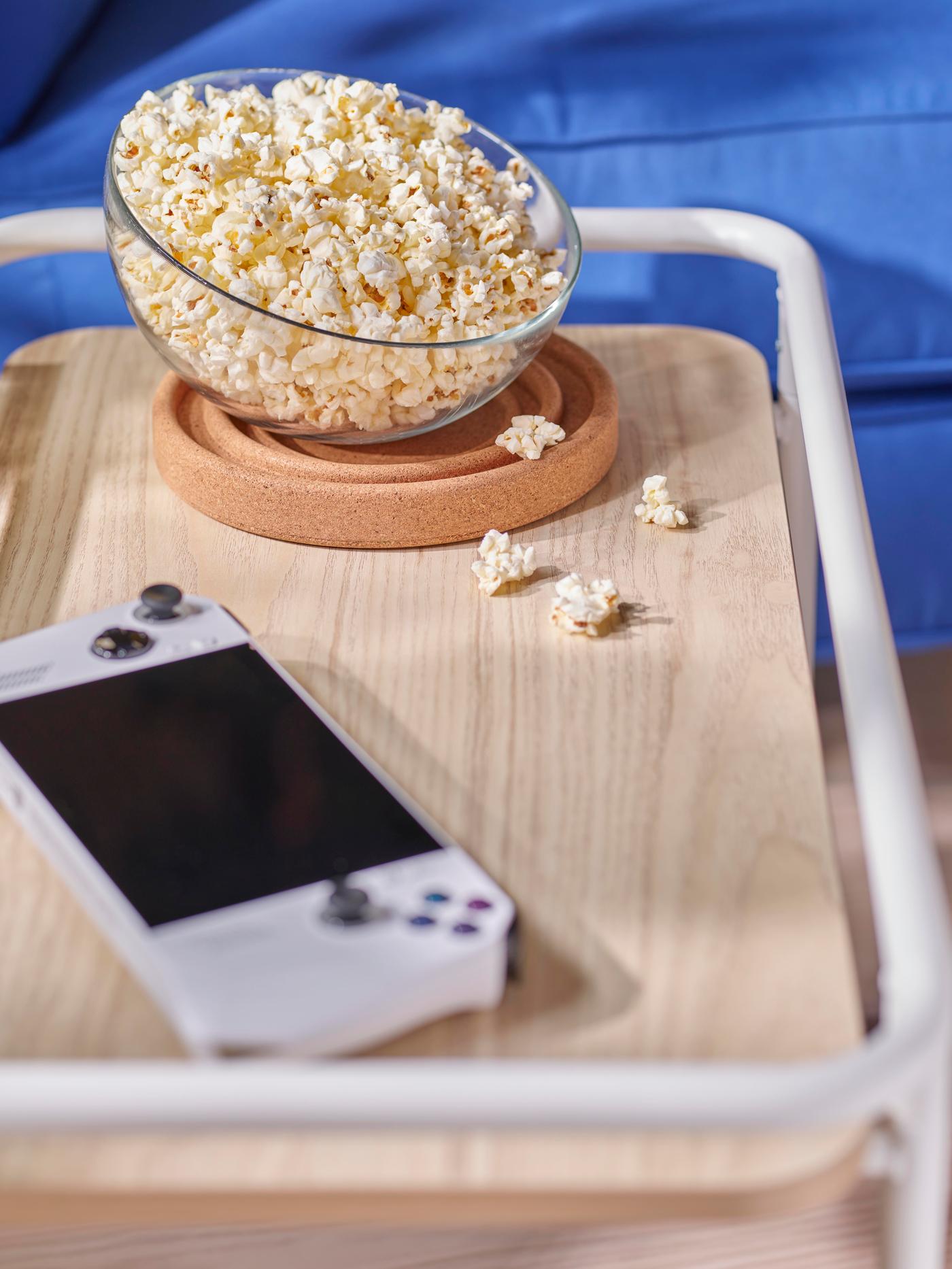 An IKEA TINGBY side table in dark grey over a dark grey rug, various magazines and a phone over it.