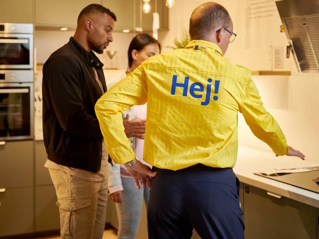 An IKEA worker helping two costumers