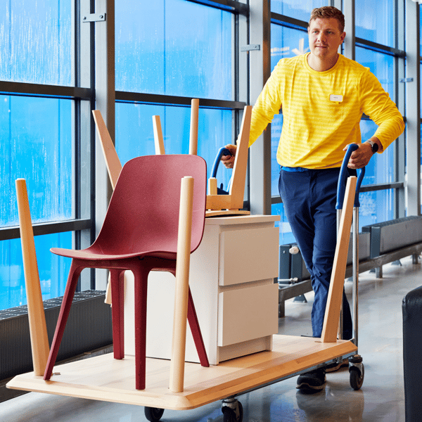 An IKEA worker wheeling along a trolley with IKEA furniture on it.