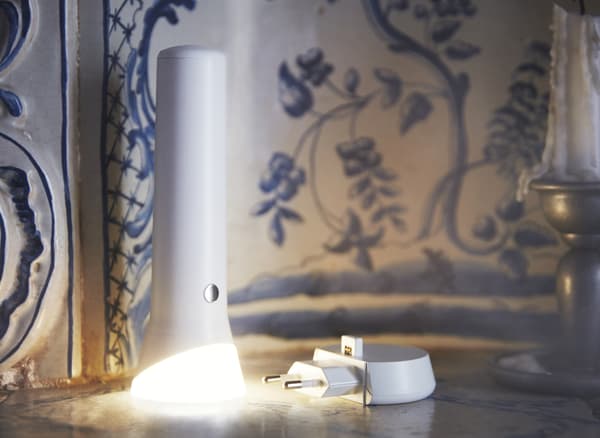 An illuminated torch and charging plug on a surface.