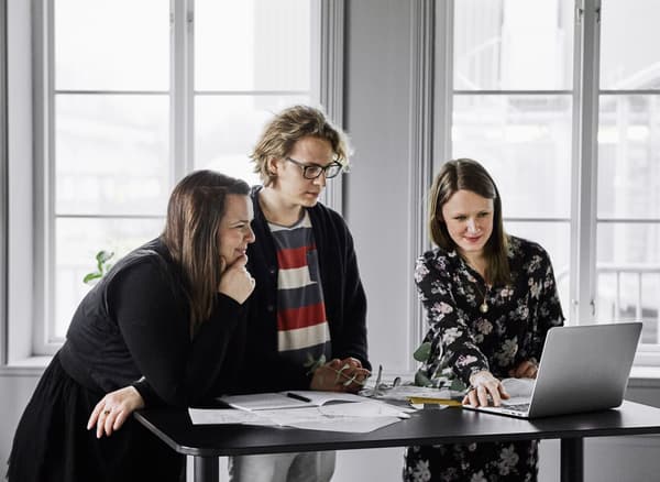 An interior designer and a couple planning a wedding gathered around a work table 