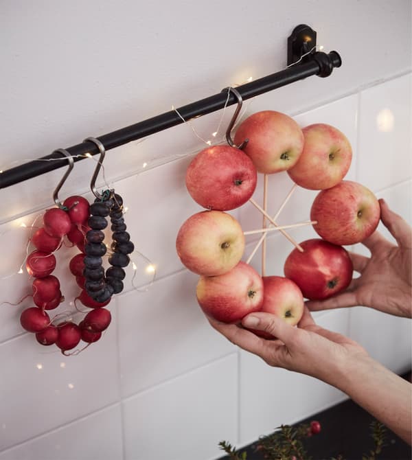 An interior designer hangs an apple arrangement over a kitchen counter.