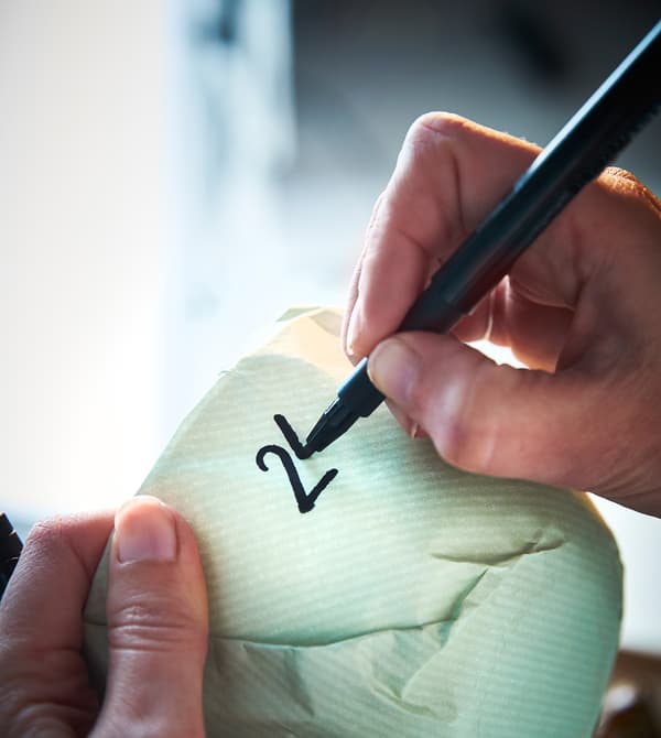 An interior designer numbers each wrapped piece of dinnerware.