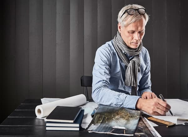 An interior stylist sitting at a table, flipping through magazines and sketching inspiration for his dream kitchen