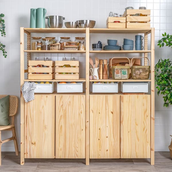 An IVAR pantry unit in a kitchen, holding various jars, cookware, storage baskets, and containers. 