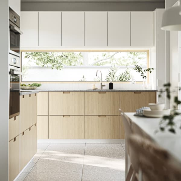 An L-shaped IKEA kitchen with white wall units and base units with wood-look fronts with integrated handle from the METOD kitchen system