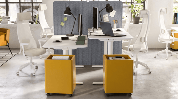 An office setting with white sit/stand desks and yellow cabinets.