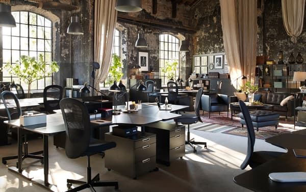 An office space with vintage room decor and modern IKEA BEKANT black work desks and FLINTAN black high-back swivel chairs.