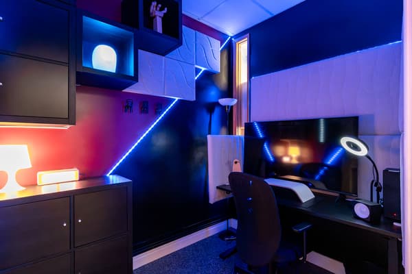 An office with black desks and storage, lit up with blue neon lights.