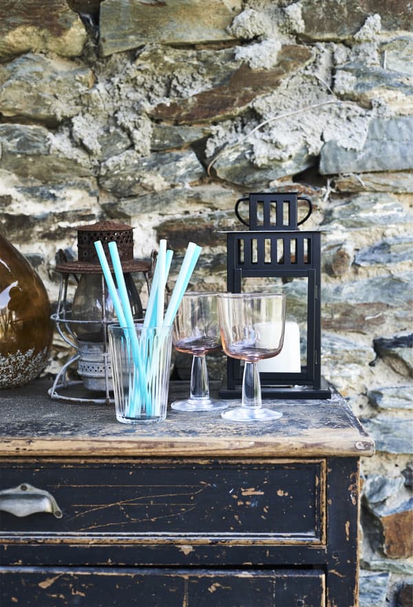 An old sideboard with glasses and a lantern on top.