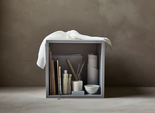 An open cabinet filled with art supplies such as paint brushes.