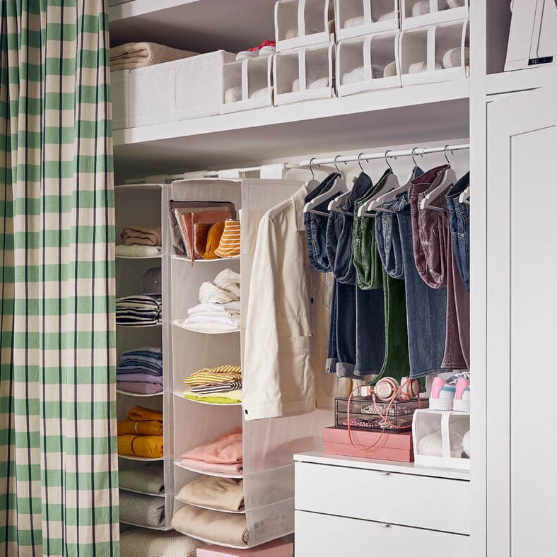 An open, customised clothing storage solution with hanging space, overhead boxes, and a curtain closure